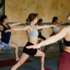 Bali yoga retreat: women in warrior pose, serene atmosphere for well-being and mental clarity